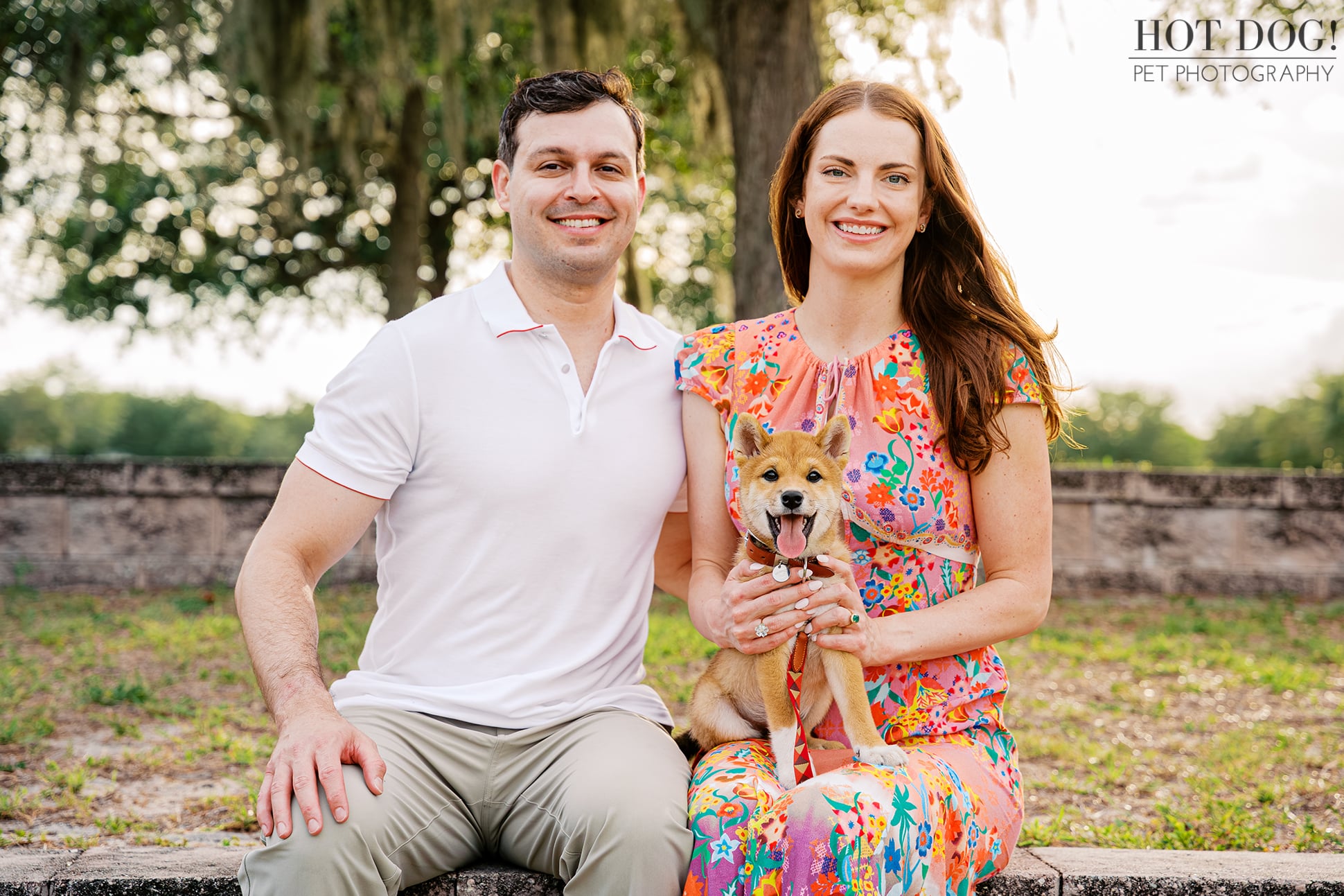 Alyssa and Mike posing with their smiling Shiba Inu puppy Auro during a family pet photography session in Orlando.