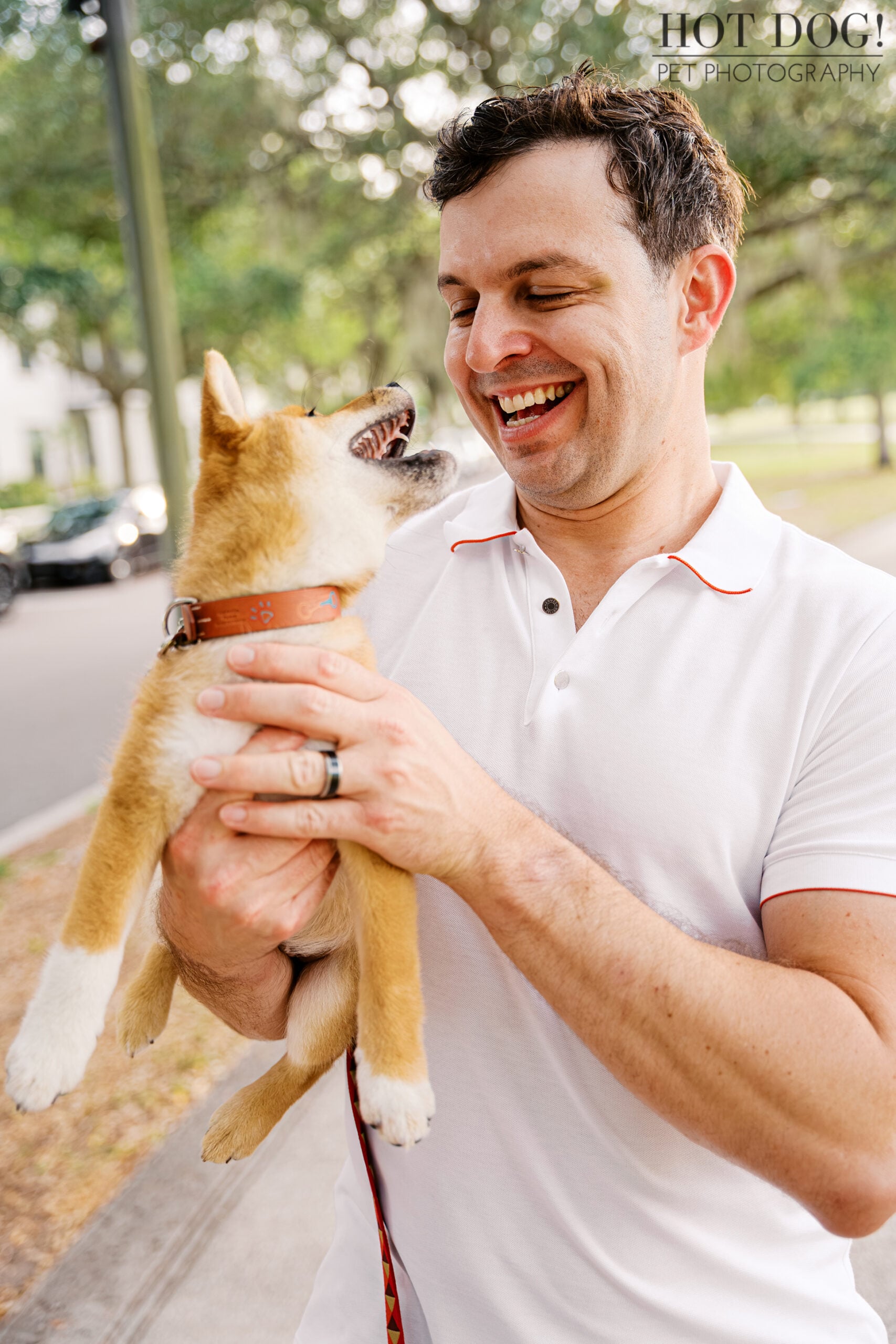 Mike laughing with Shiba Inu puppy Auro in his arms during a playful moment at their Orlando pet photography session.