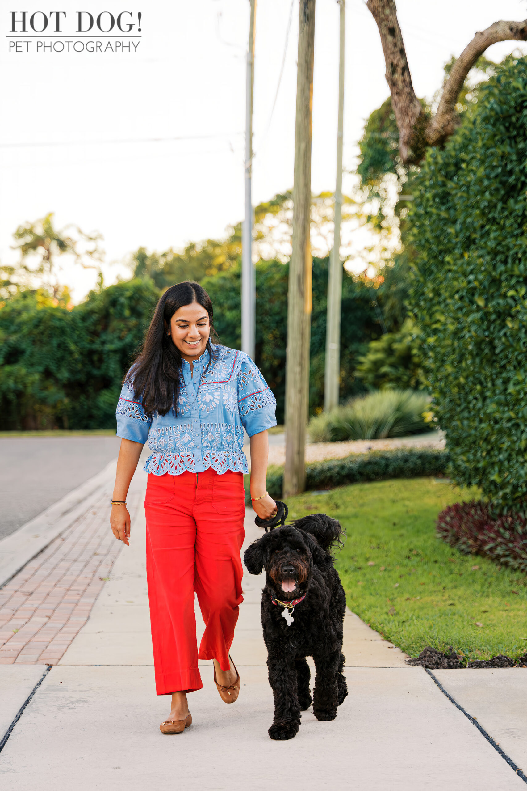 Selavi walks Banjo down the sidewalk in their Winter Park neighborhood, both smiling as Banjo trots happily by her side.