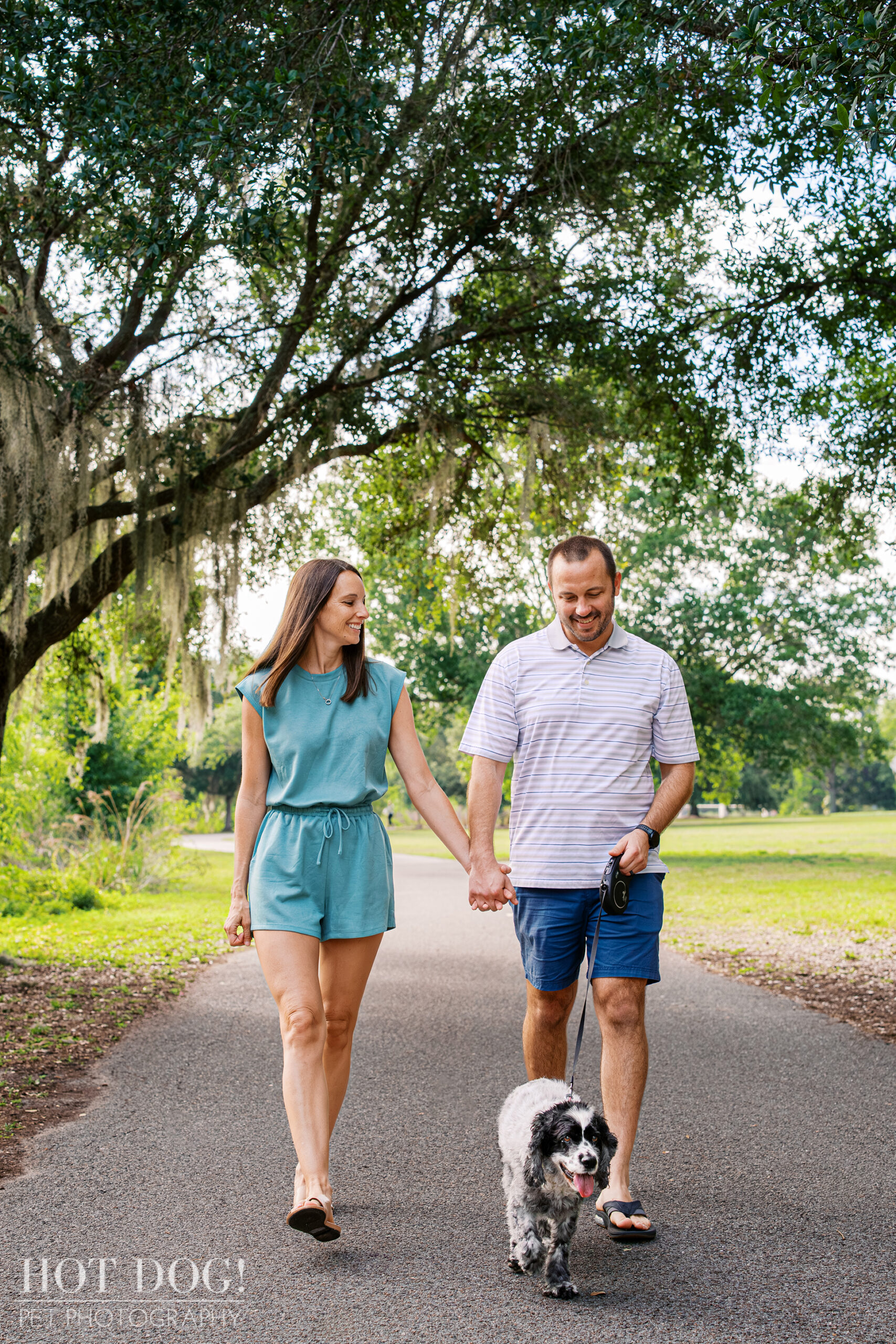 Tiffany and Rob walking with their senior cocker spaniel Ella along a tree-lined path at Harbor Park in Baldwin Park.