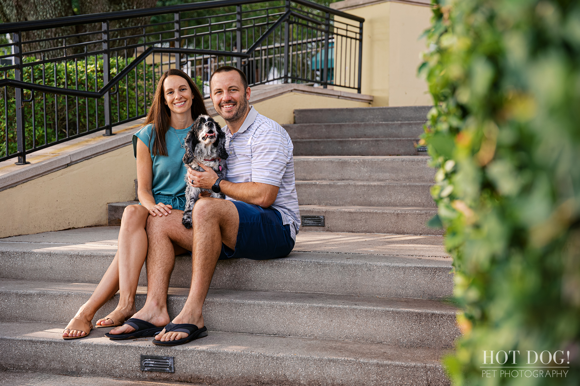 Tiffany and Rob sitting together with Ella on outdoor steps during their family pet photography session at Harbor Park in Baldwin Park.