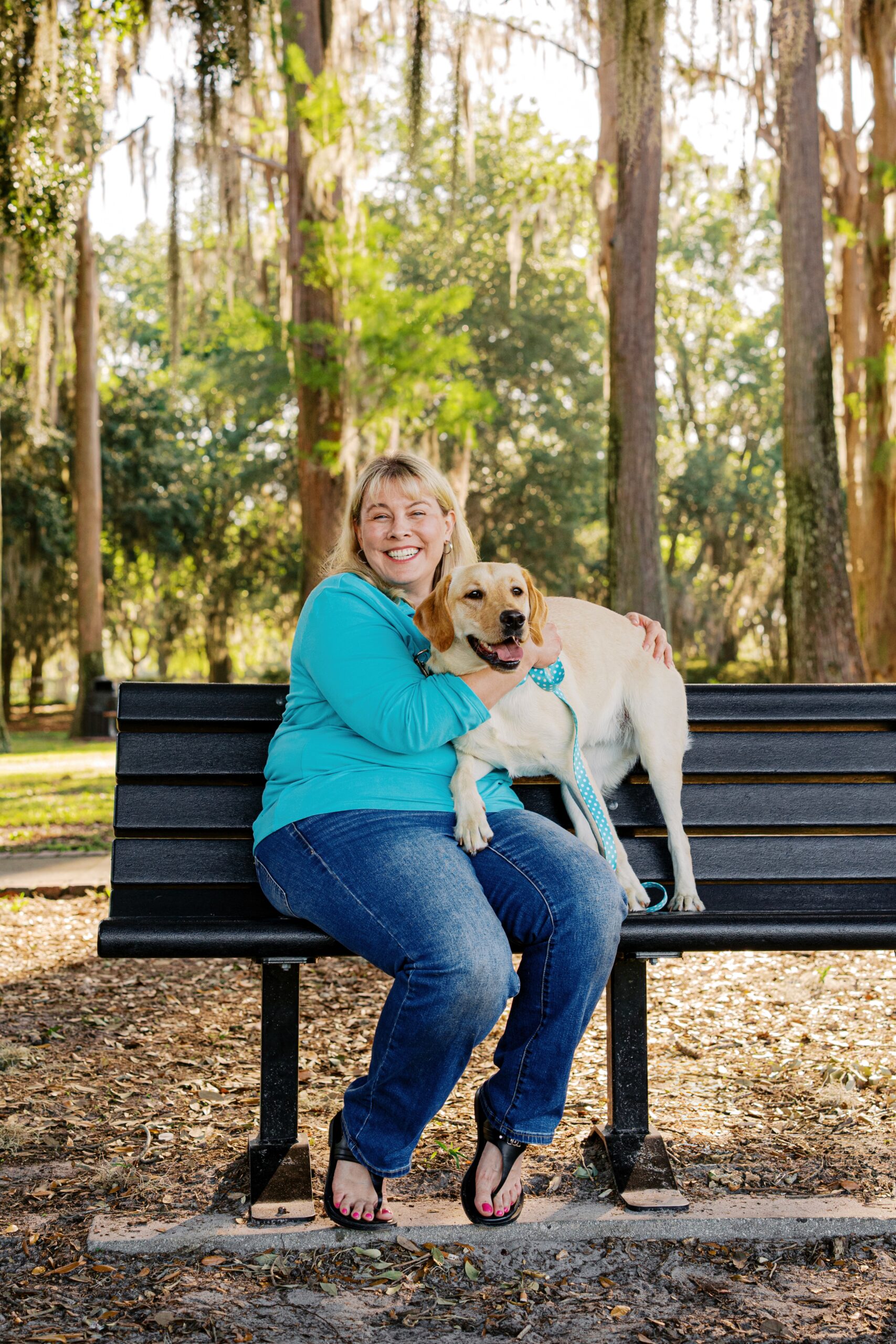 Woman hugging her yellow Labrador Retriever while sitting on a park bench at Cypress Grove Park.