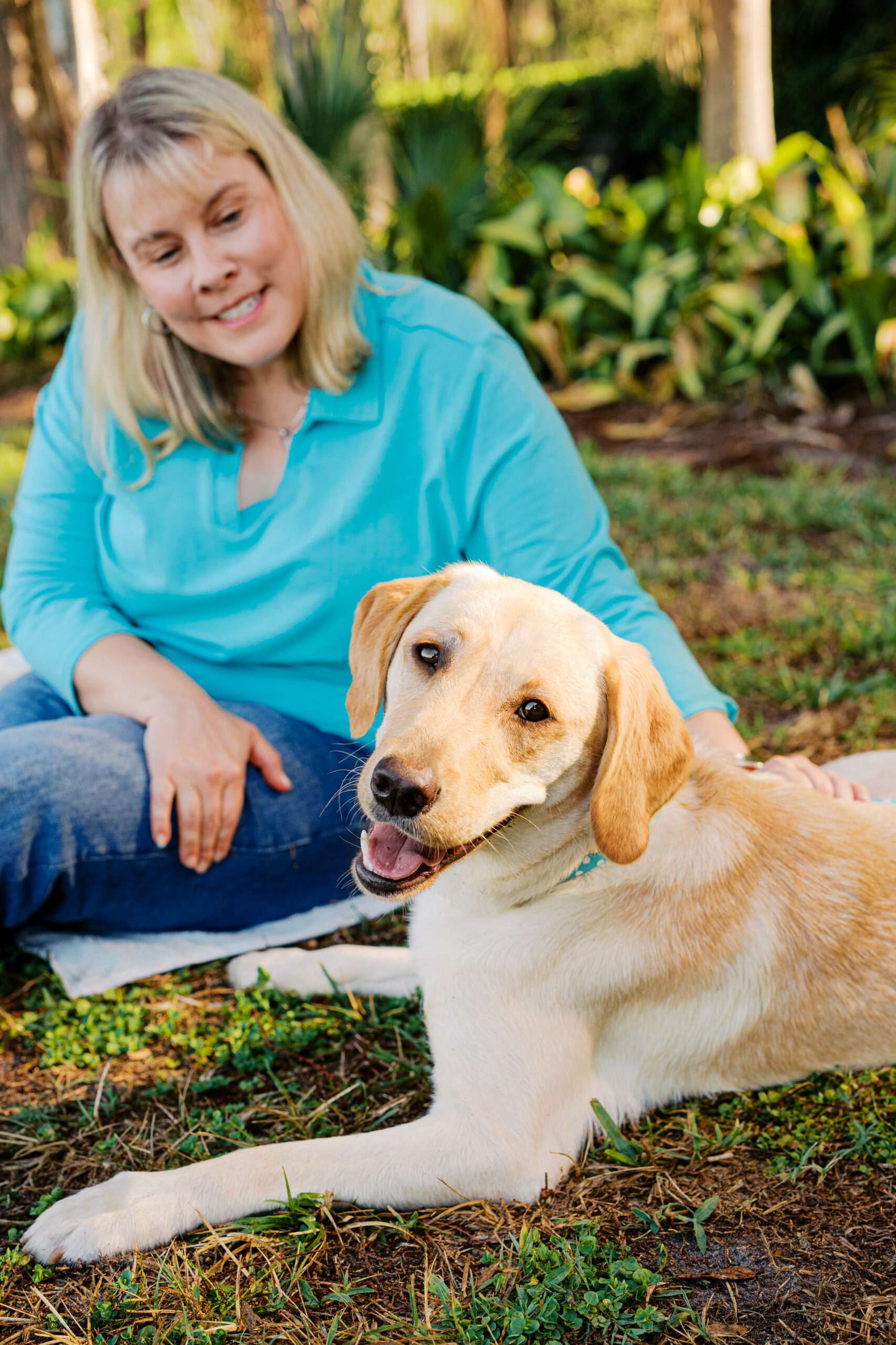 Woman and her smiling yellow Labrador Retriever posing together outdoors at Cypress Grove Park.