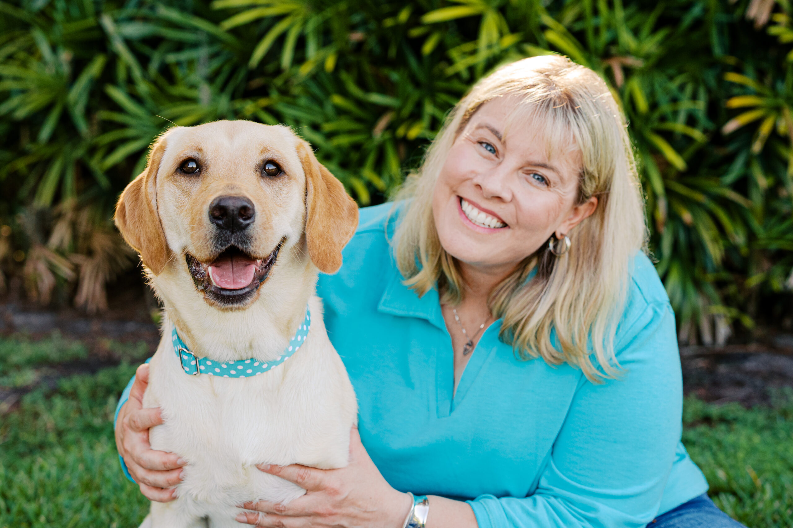 Woman and her smiling yellow Labrador Retriever posing together outdoors at Cypress Grove Park.