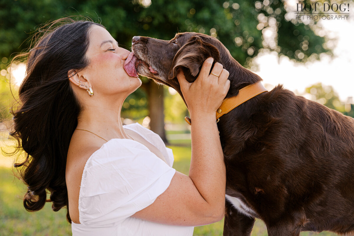 Gemma gives Anne a big kiss during their outdoor pet photography session, capturing the affectionate bond they share.