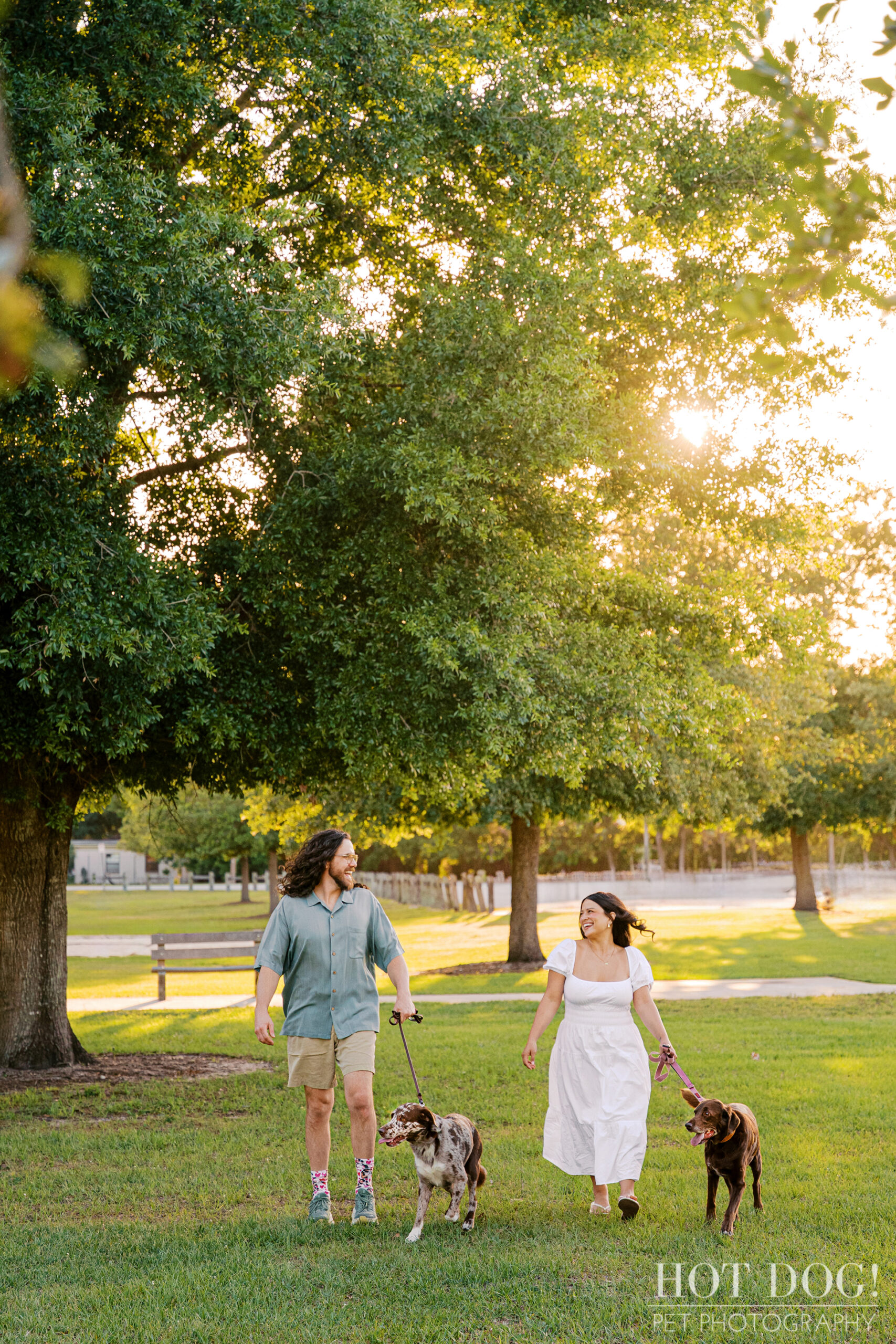 Anne and Jared walk through Lake Druid Park with Gemma and Ellie during a relaxed outdoor dog photography session at sunset.