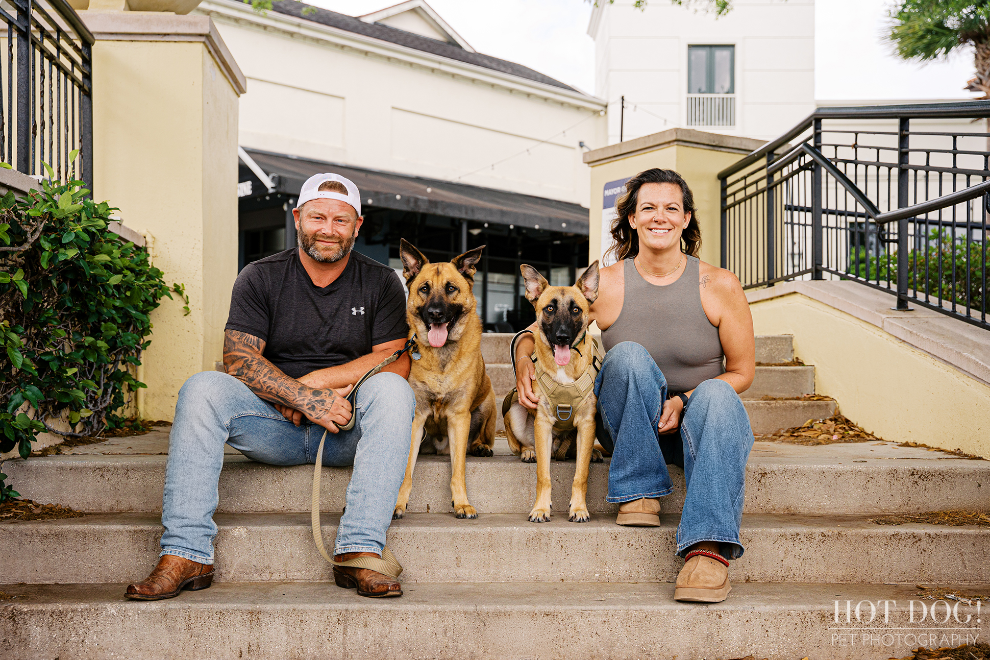 Krystle and Scott sitting on steps with their dogs Maverick and Goose in Baldwin Park, smiling during a relaxed outdoor pet photography session.