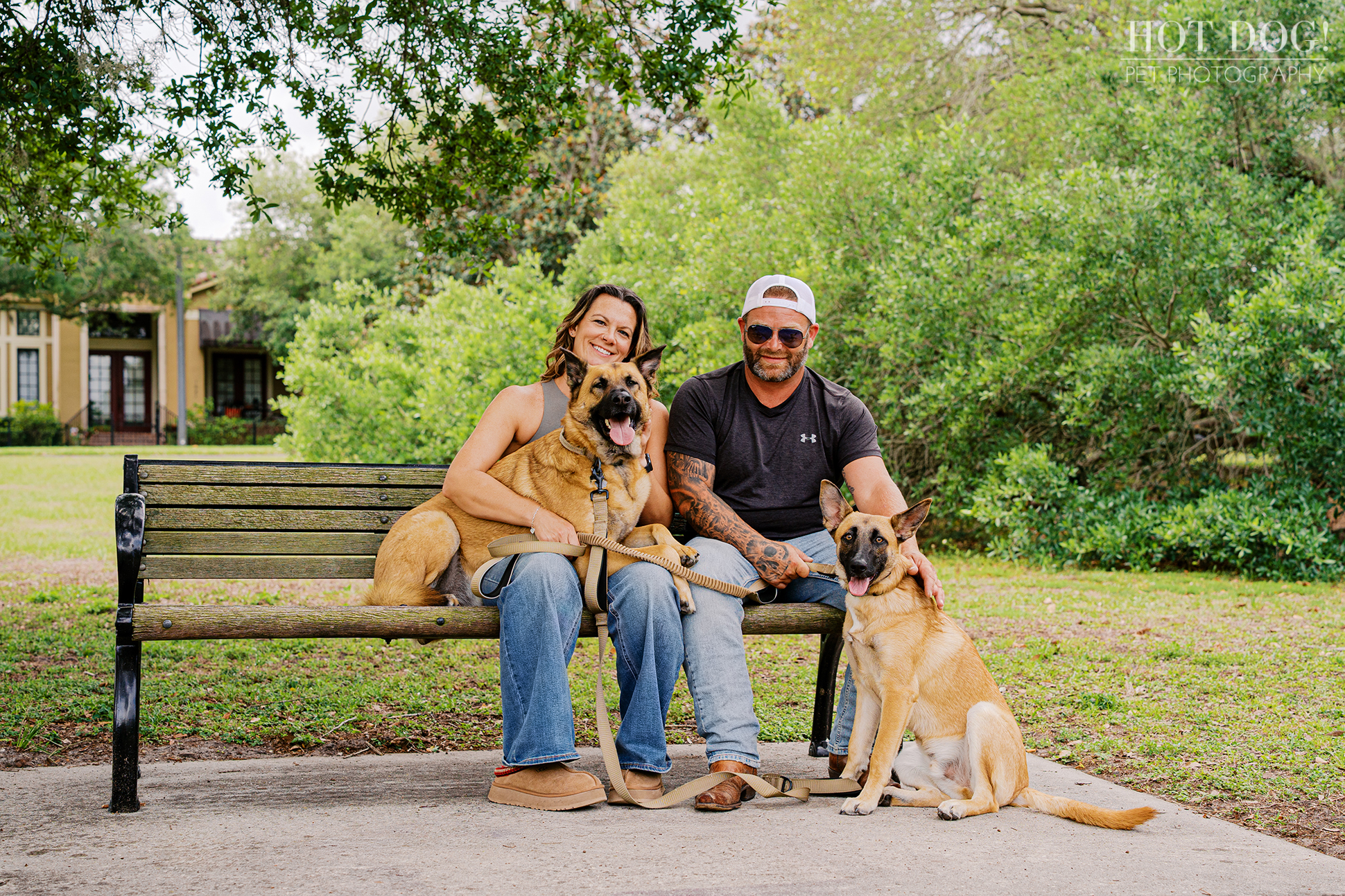 Krystle and Scott sitting on a park bench with Maverick and Goose in Baldwin Park, surrounded by greenery during a relaxed pet photography session.