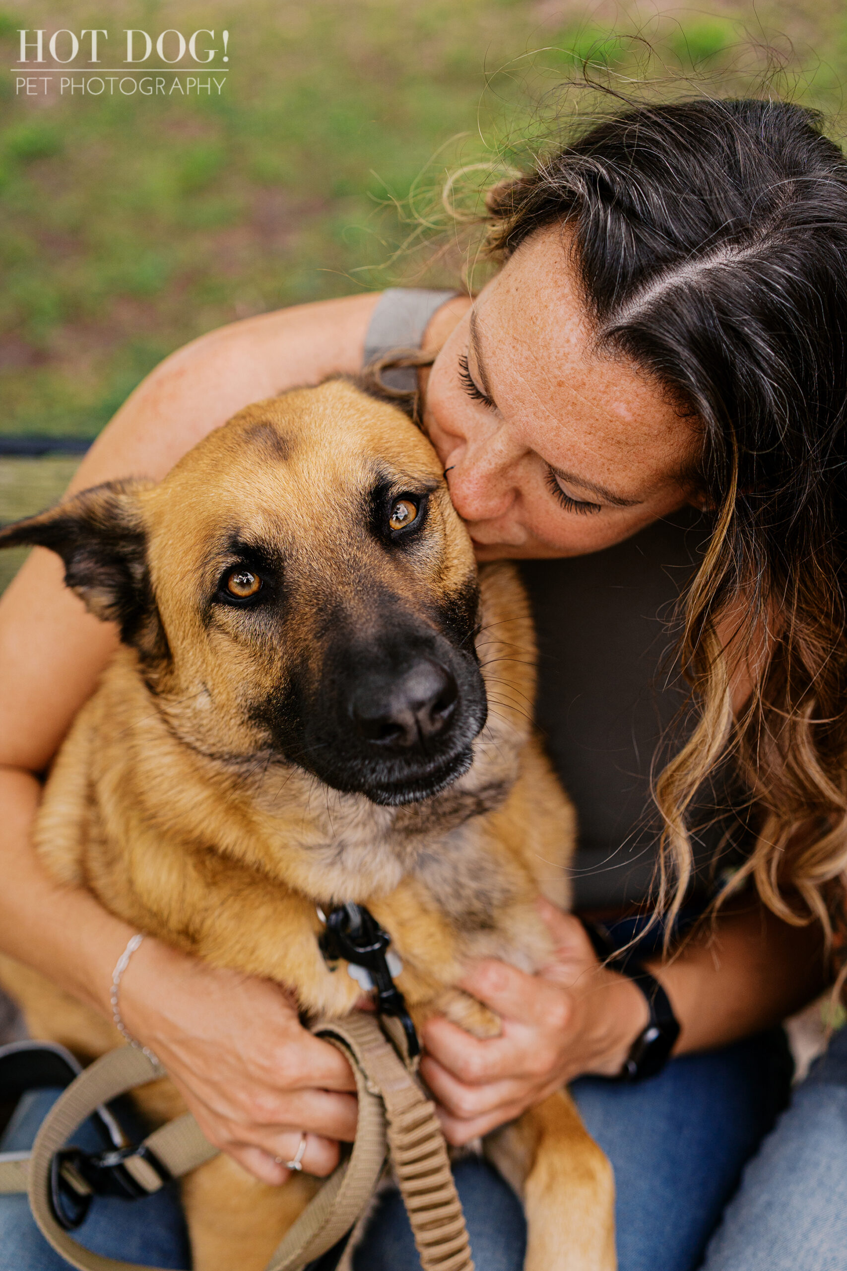 Krystle kissing Maverick, the older tan and black dog with a floppy ear, during a candid outdoor pet photography moment in Baldwin Park.