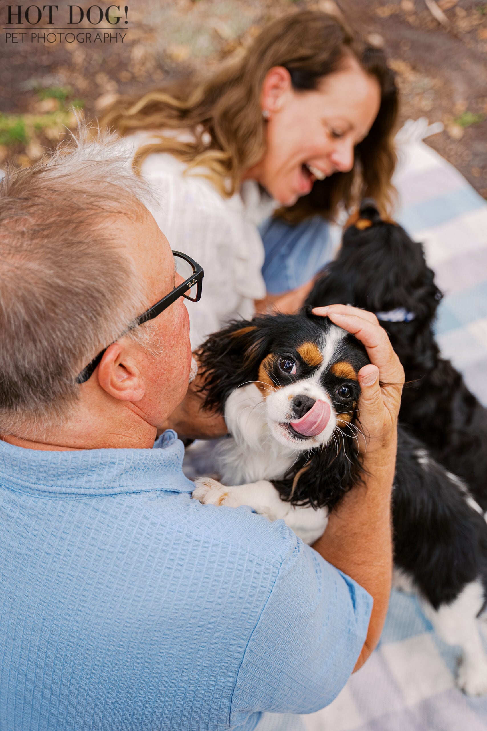 James cuddling Jerzee as the playful Cavalier King Charles Spaniel licks her nose during a natural family pet photography session in Florida.