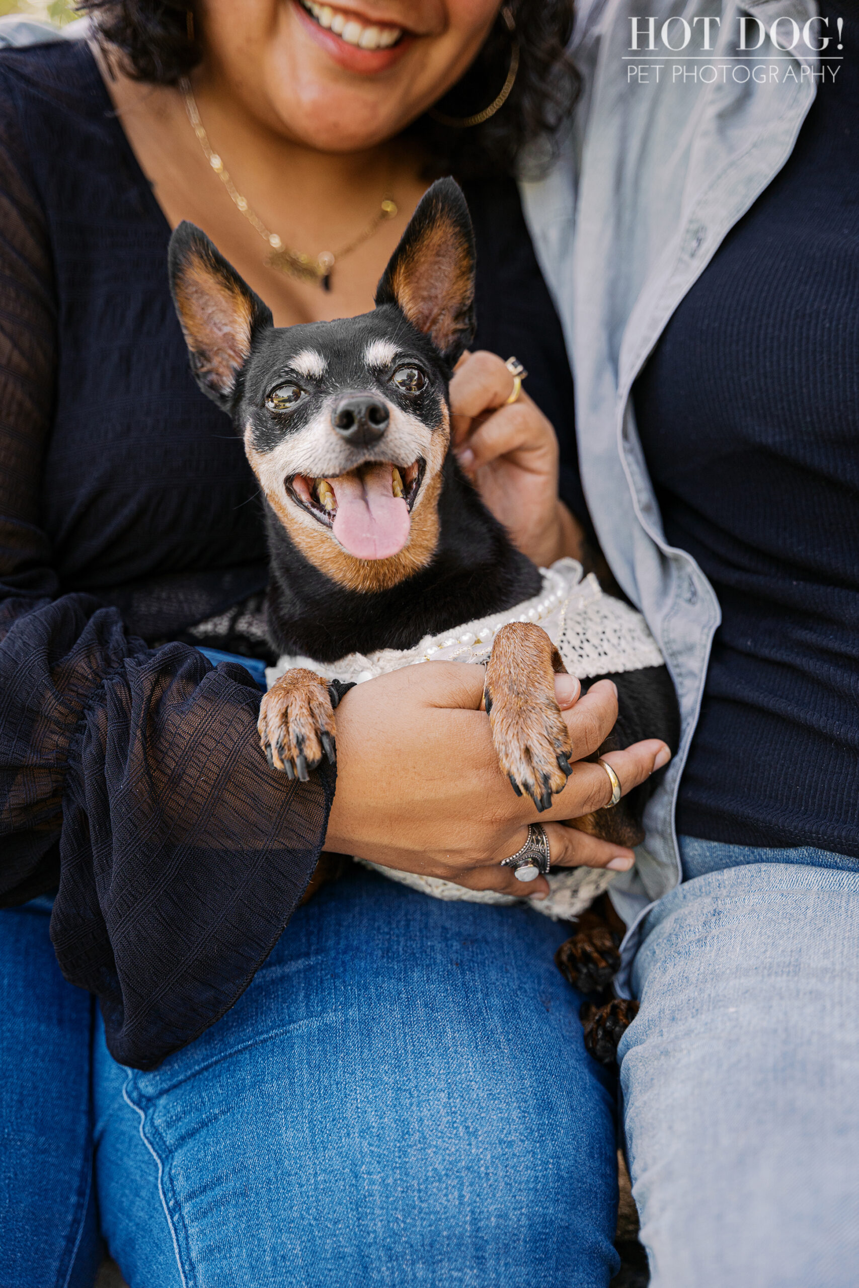 Close-up of Kiki lying on Gabriela’s lap, smiling happily in her white lace dress.
