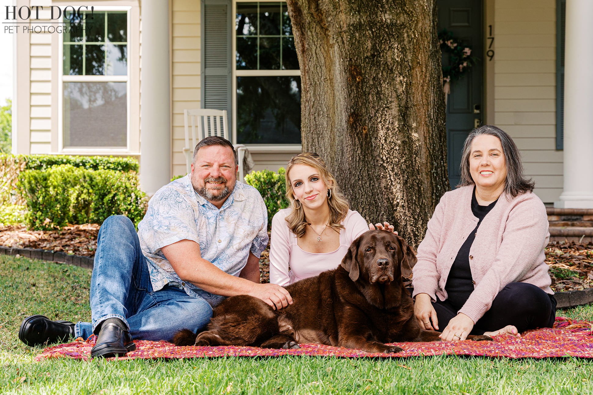 Kona, a beloved chocolate Labrador Retriever, relaxes on a colorful blanket with the Crowe family during an at-home pet photography session in Oviedo, Florida.