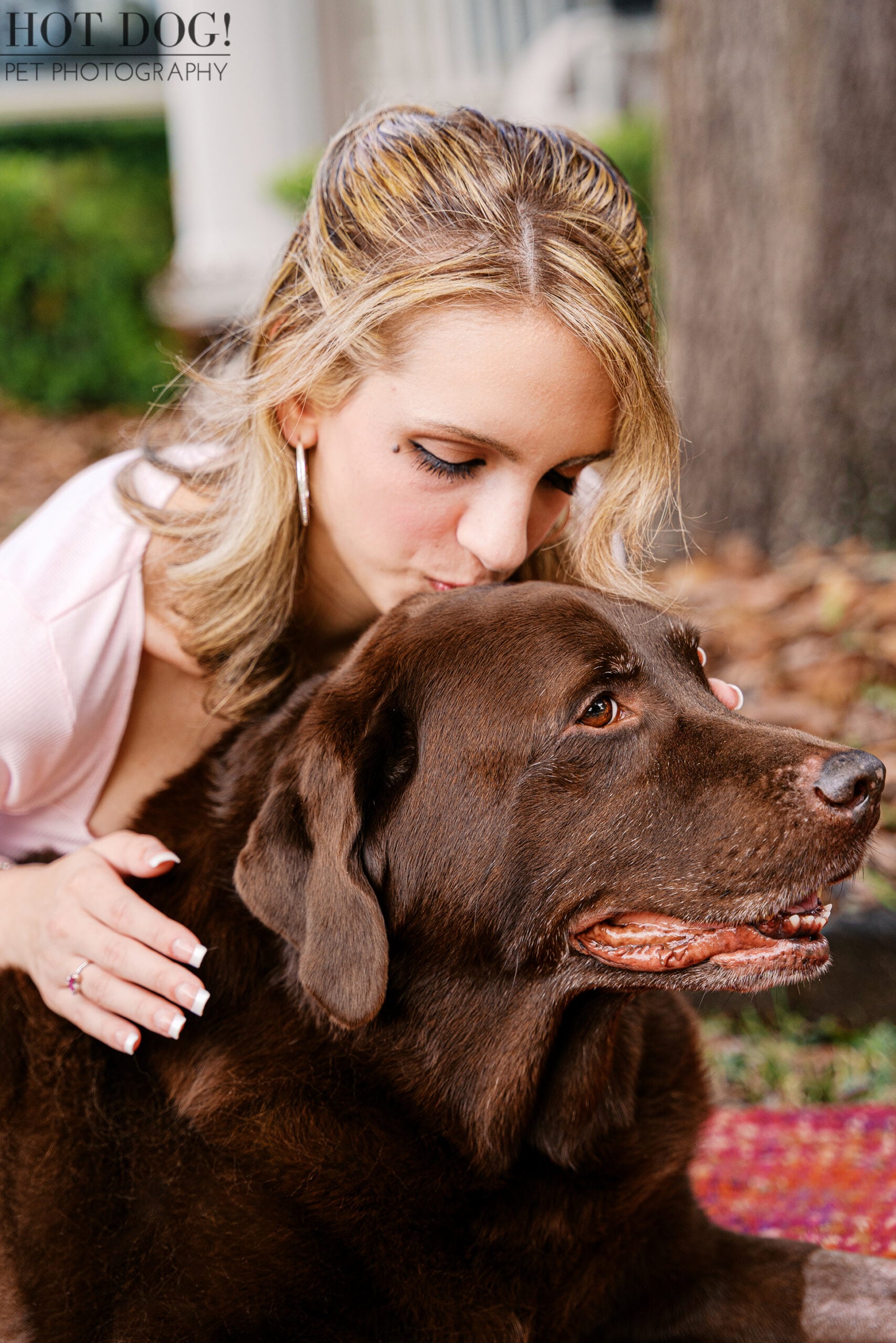 Regina gently kisses Kona, her family's beloved chocolate Labrador, during an emotional senior dog photography session in Oviedo, Florida.