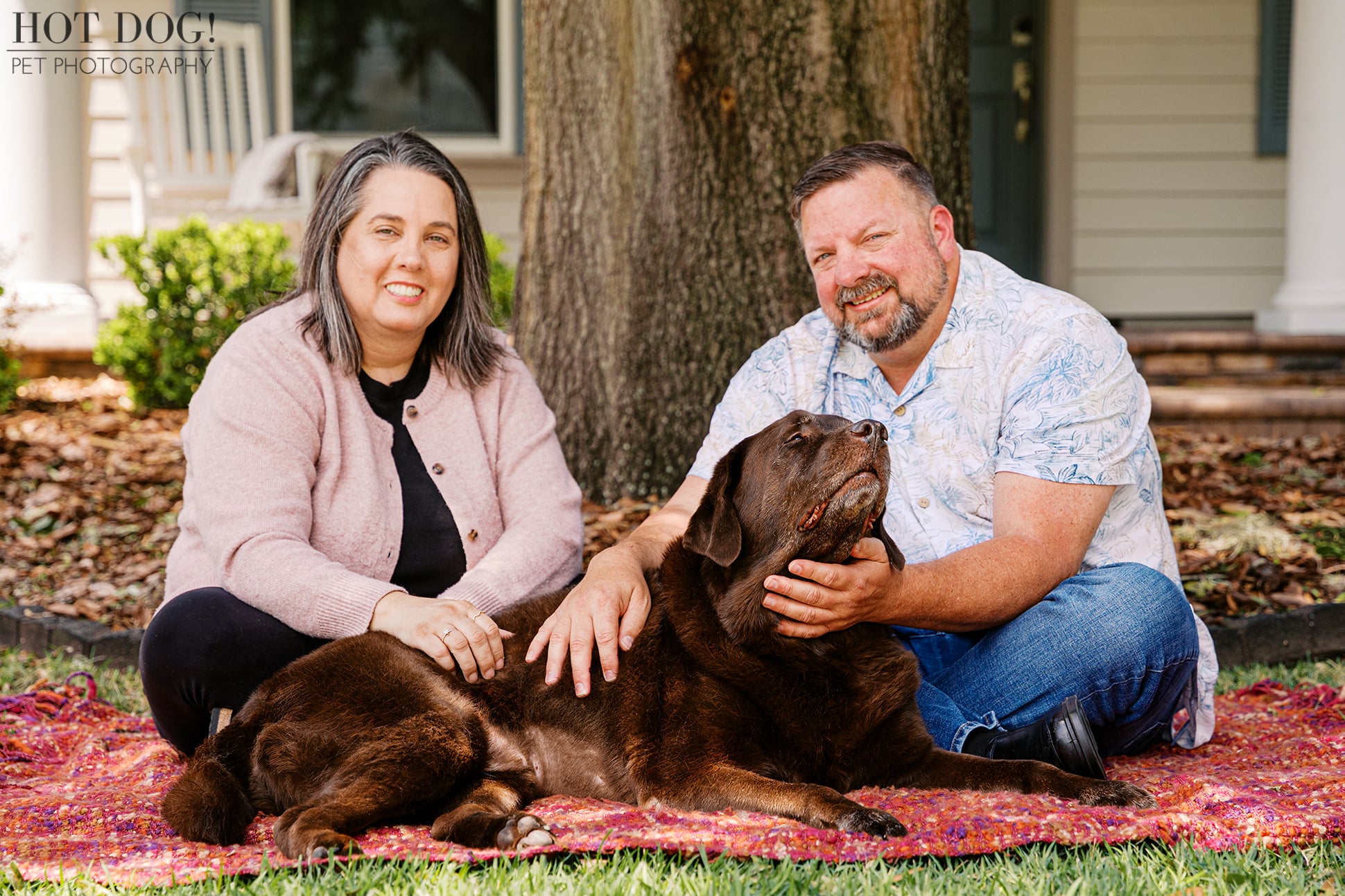 Jennifer and James sit with their beloved chocolate Labrador, Kona, sharing an affectionate moment during a senior dog photography session at their Oviedo home.