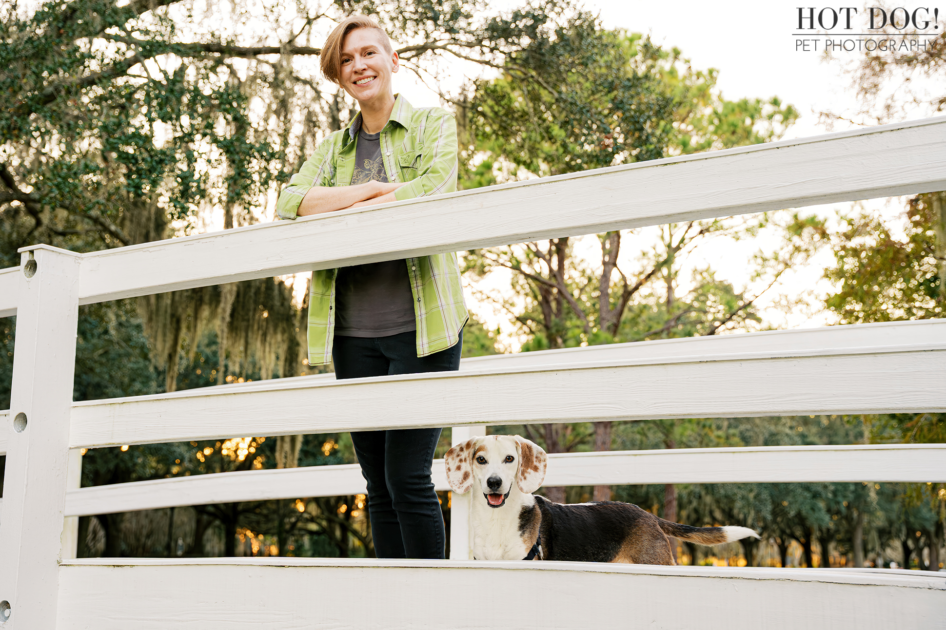 Melanie standing on a white wooden bridge while her tri-color beagle Leonard stands proudly below her.