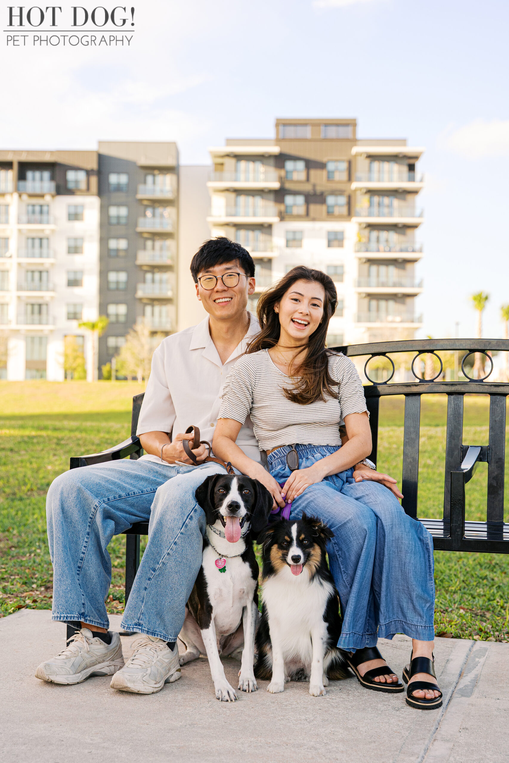 Couple sitting on a bench with their two dogs at Cranes Roost Park during a relaxed outdoor pet photography session.