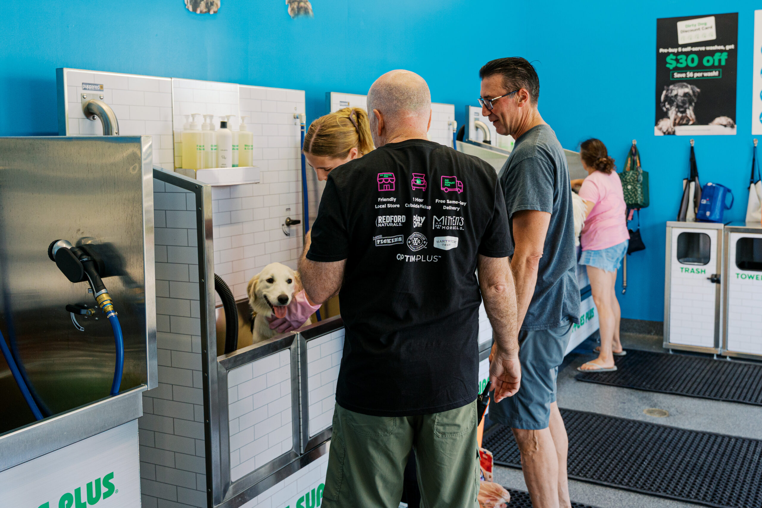 Customer using self-service dog wash station inside pet store, highlighting grooming services and in-store amenities.
