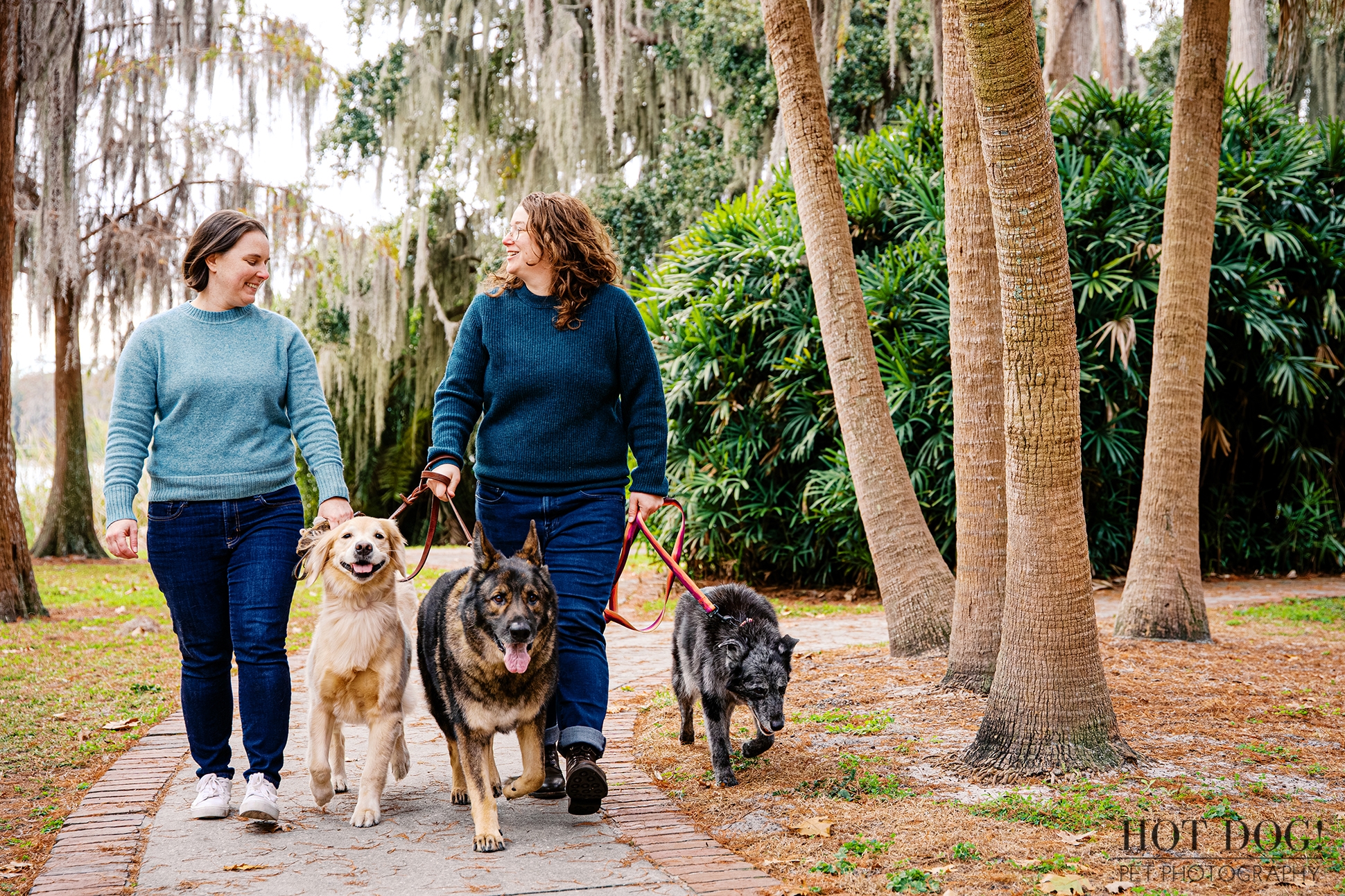 Lindsay and Aimee walking with Sadie, Appa, and Korra on a shaded path at Cypress Grove Park in Orlando.