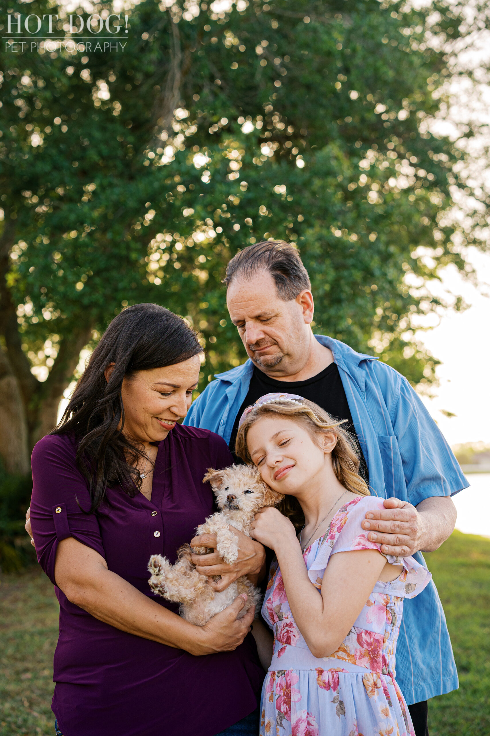 Family portrait of parents and daughter holding their senior Jack Russell Terrier during a heartfelt outdoor cherished companion session.