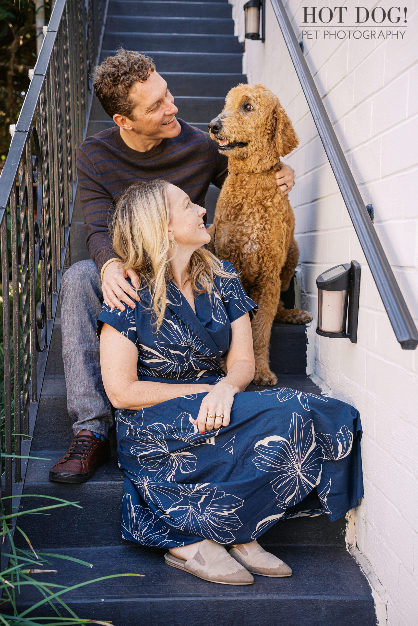 Jen and Cory sitting on an outdoor staircase with Wizard beside them, all three looking happy and relaxed during their Cherished Companion session.